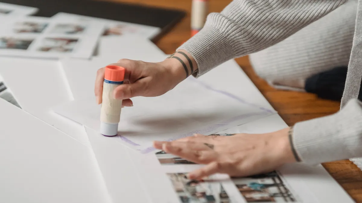 Beginner Scrapbooking Basics — The Complete Guide Hands using a glue stick on scrapbook pages