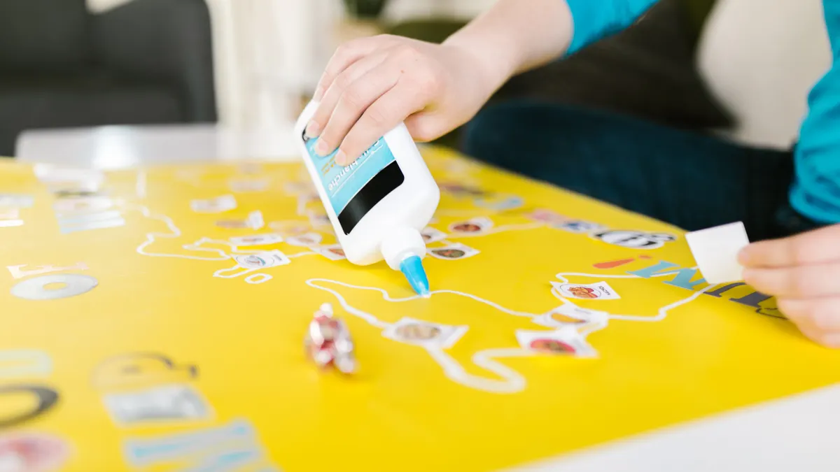 How to Choose Scrapbooking Adhesives That Won't Damage Photos Hand squeezing glue onto craft paper