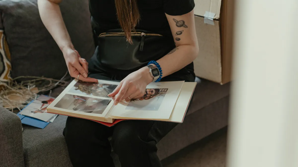 How to Preserve Photos in Scrapbooks Without Damaging Them Hands placing photos into a scrapbook album
