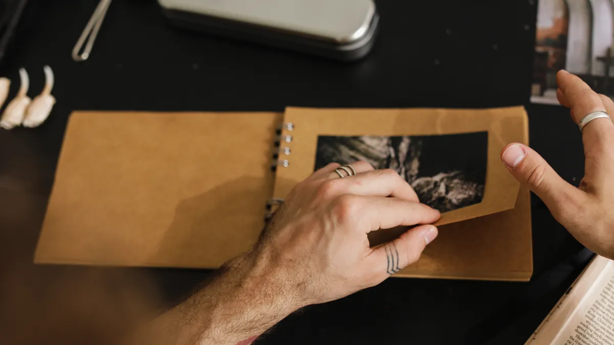 How to Preserve Photos in Scrapbooks Without Damaging Them Hands inserting a photo into a scrapbook
