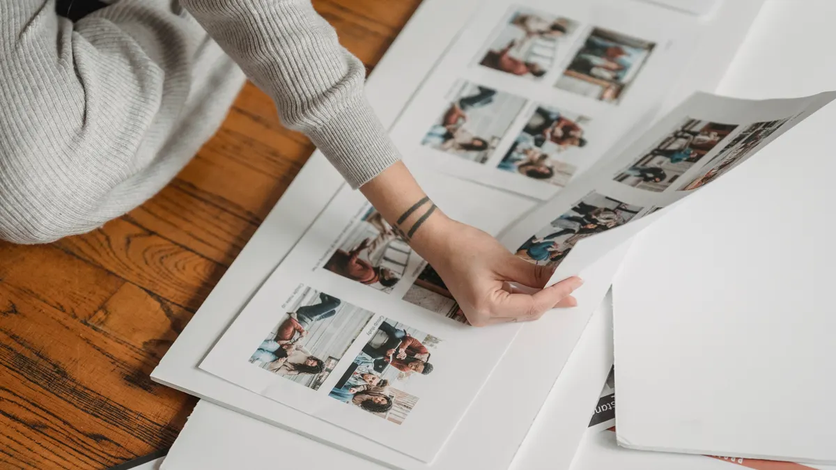 Person arranging printed photos in an open scrapbook
