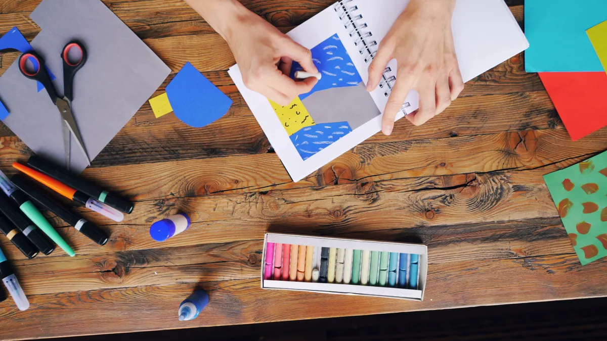 hands creating a scrapbook layout with paper pieces